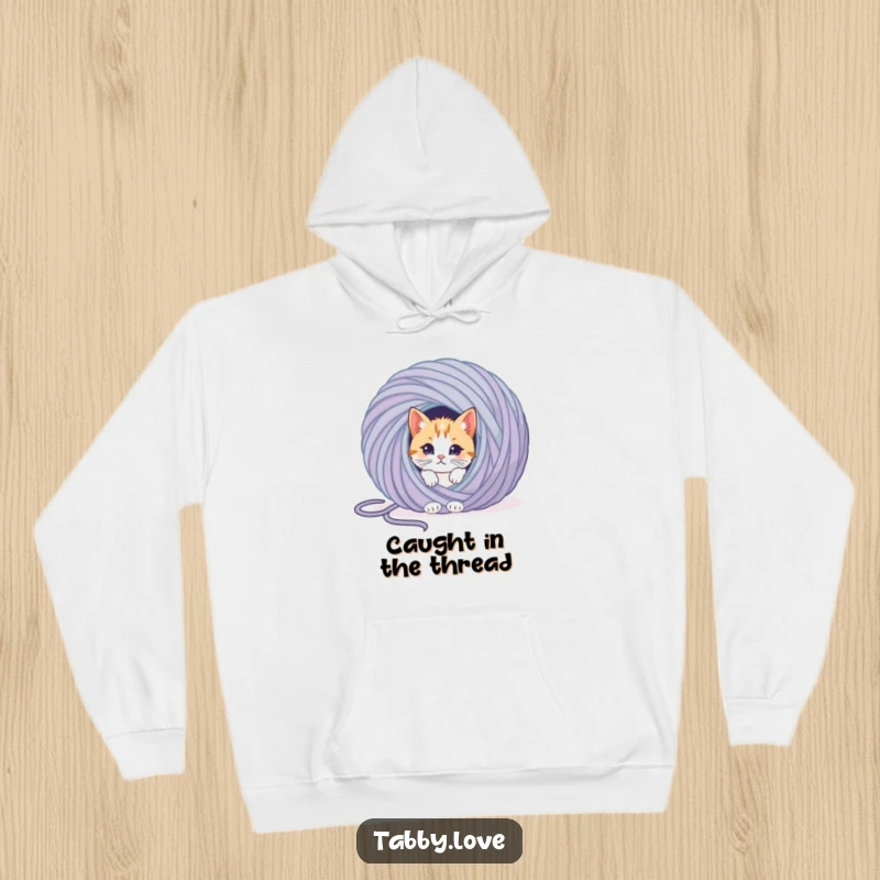Funny cat hoodie featuring a curious kitten emerging from a huge ball of yarn, showing off its playful, tangled adventure.